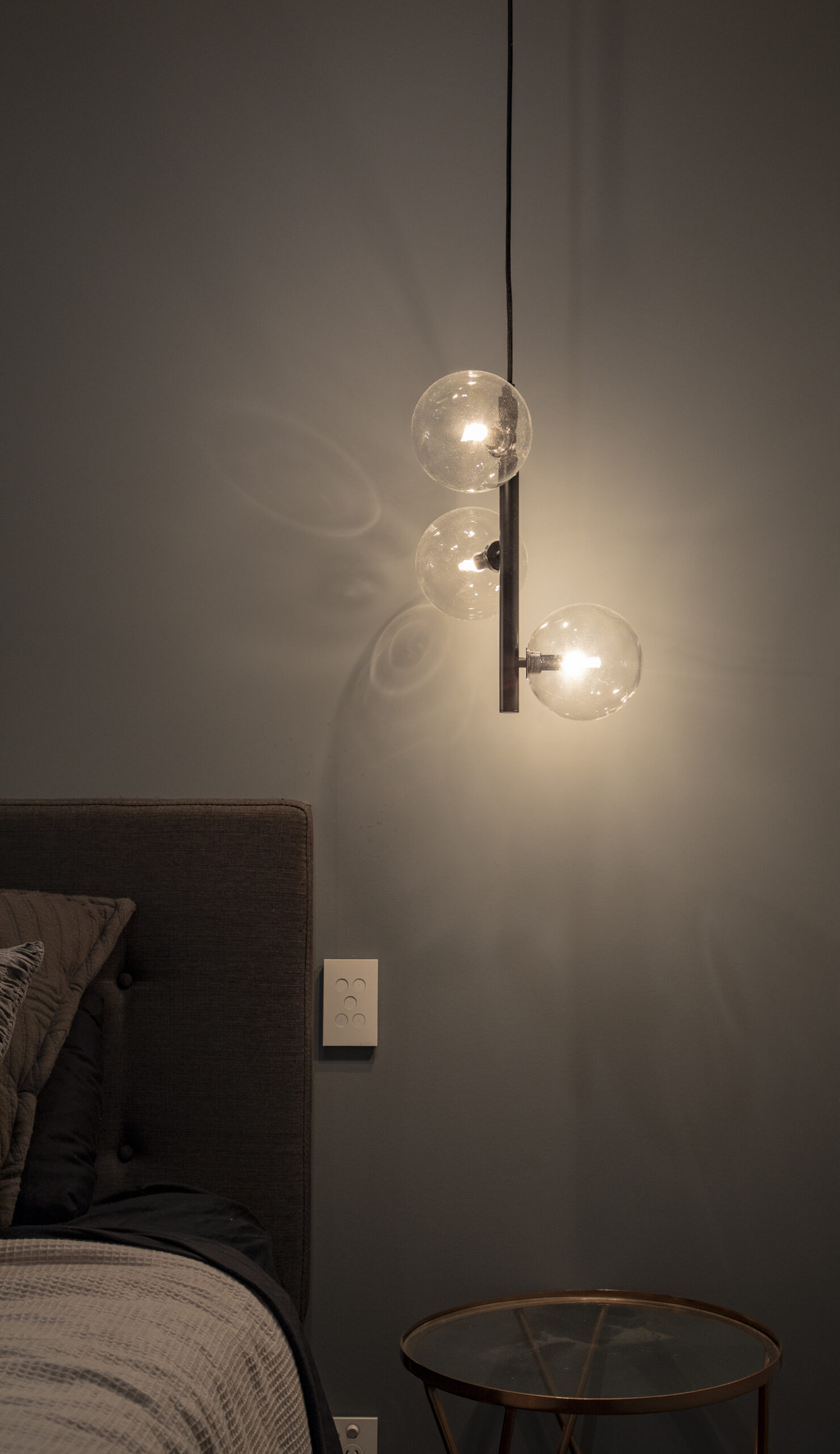 A bedroom with a bed and a lamp hanging above it.