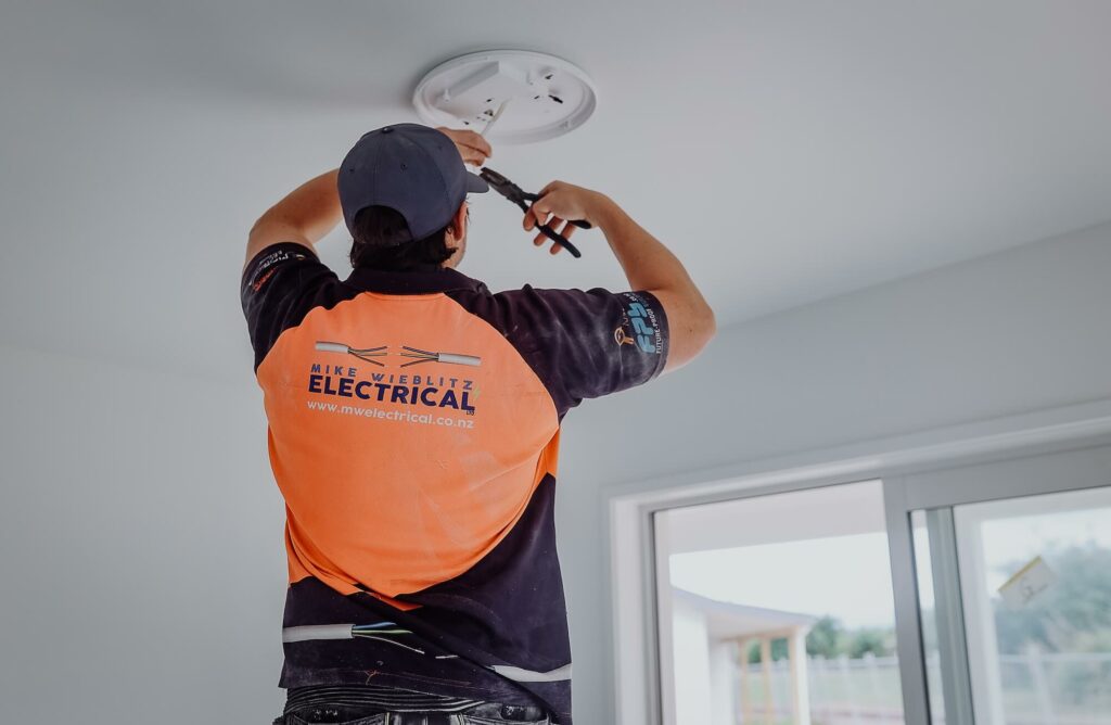 A man installing a ceiling fan in a room.
