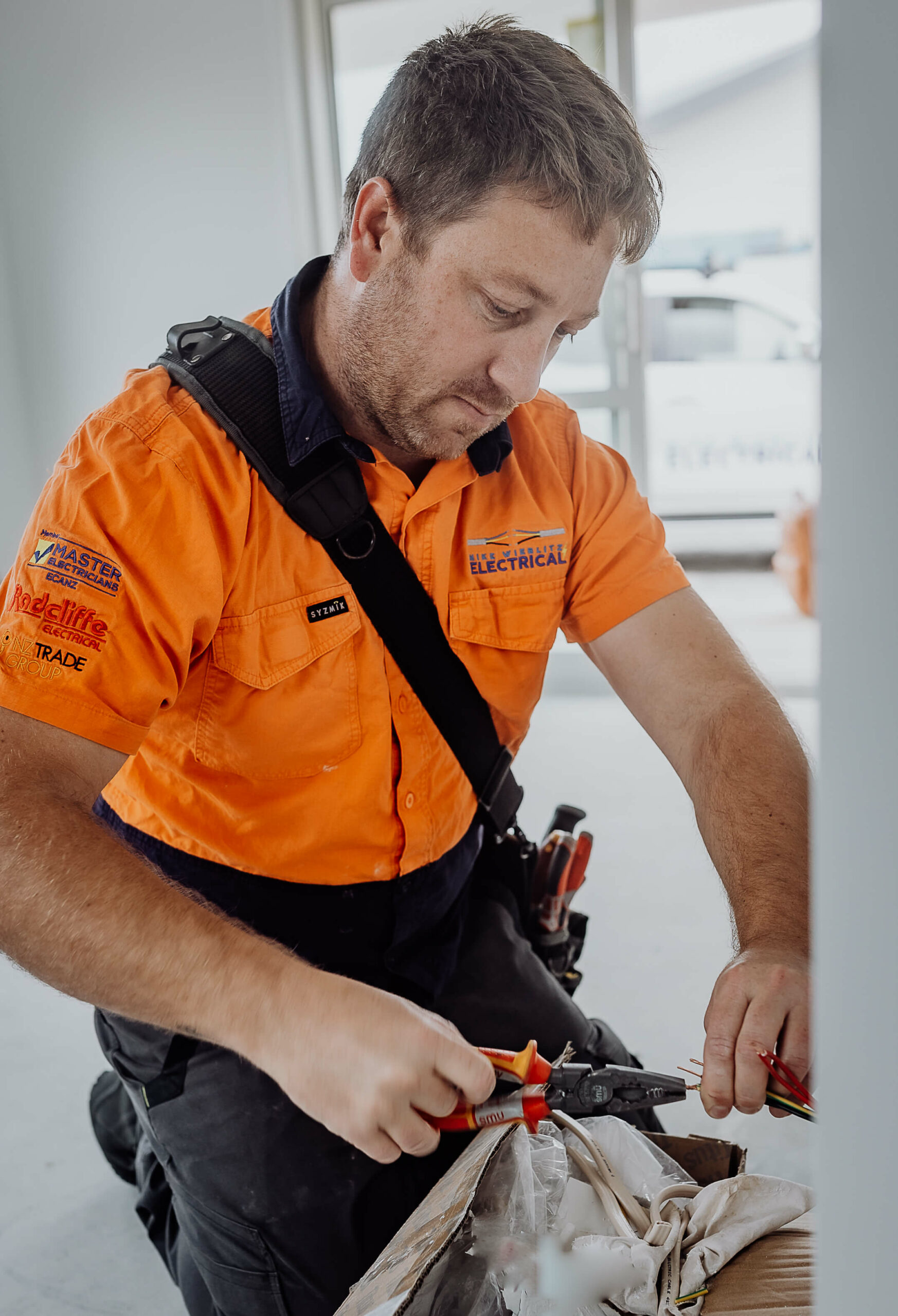 A man in an orange shirt is working on a box.