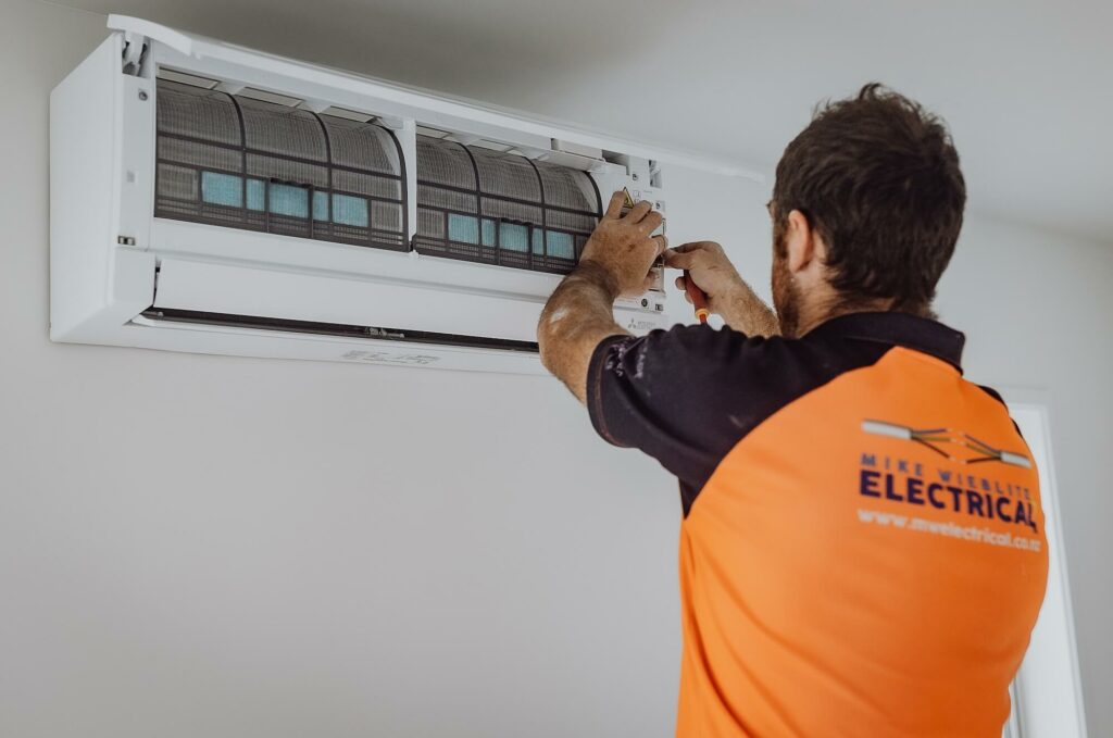 A man installing an air conditioner in a room.