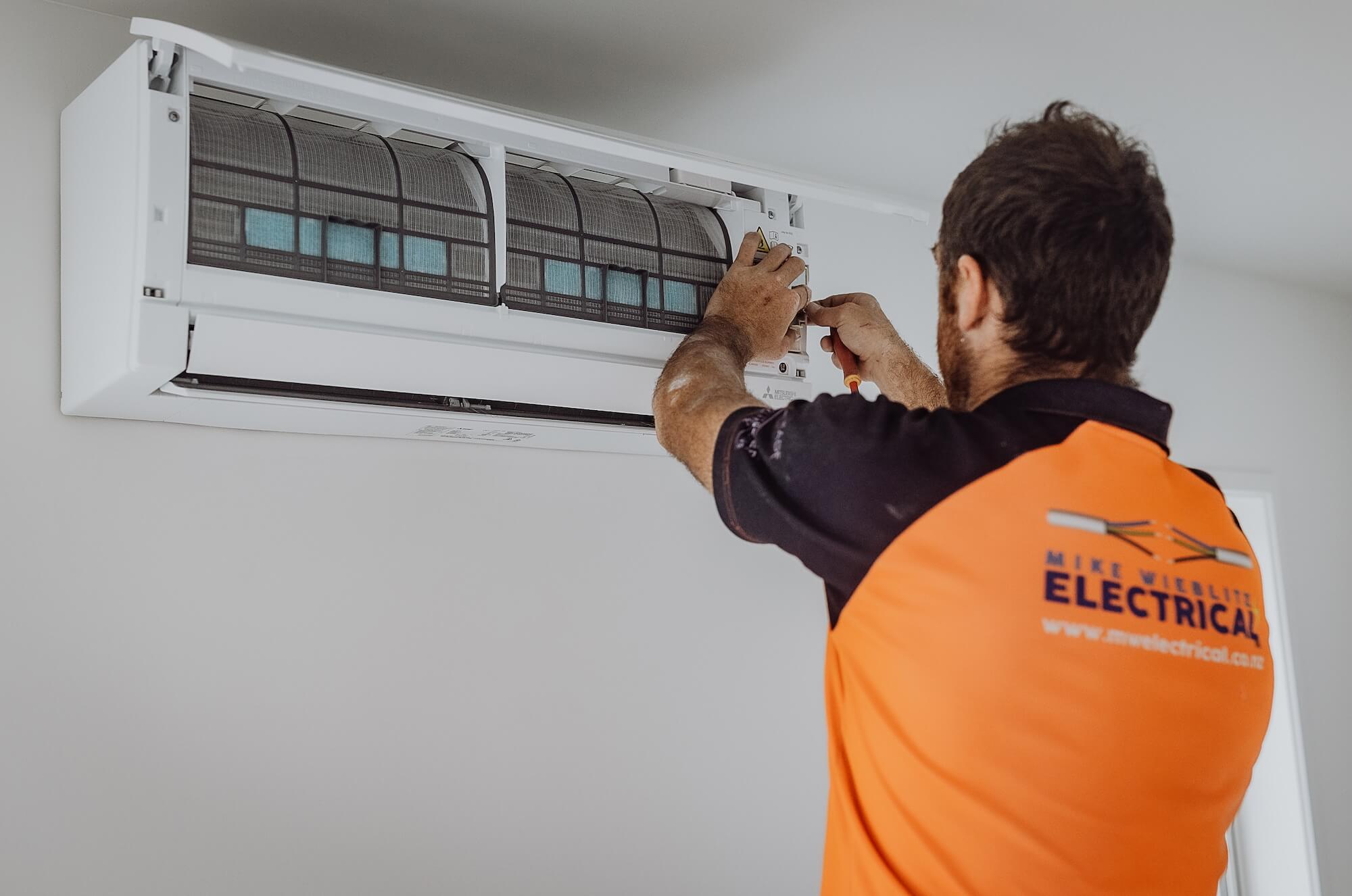 A man installing an air conditioner in a room.